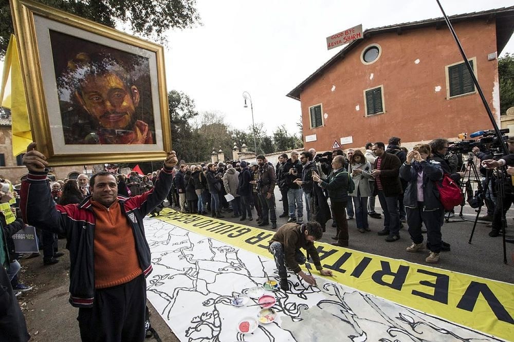 A man holds up a portrait of Giulio Regeni, the Italian student slained in Cairo, as several dozen people stage a sit-in outside Egypt's embassy in Rome. (AP Photo)