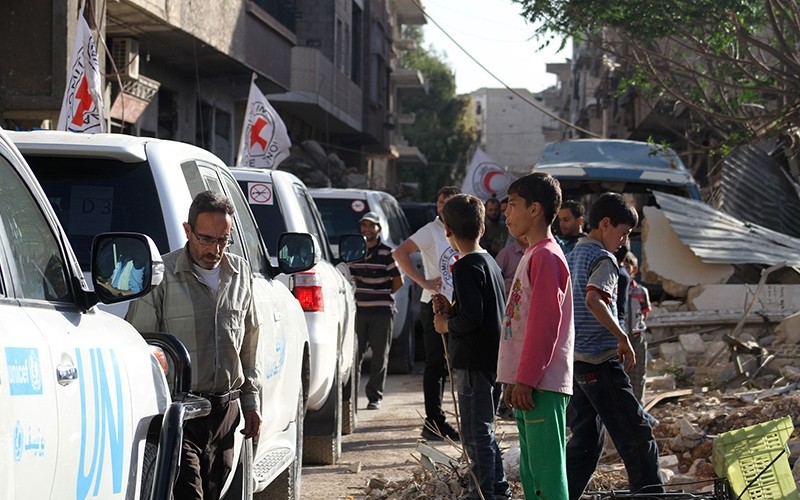 Vehicles of the International Committee of the Red Cross (ICRC), the Syrian Arab Red Crescent and the United Nations wait on a street after an aid convoy entered the rebel-held Syrian town of Daraya (AFP Photo)