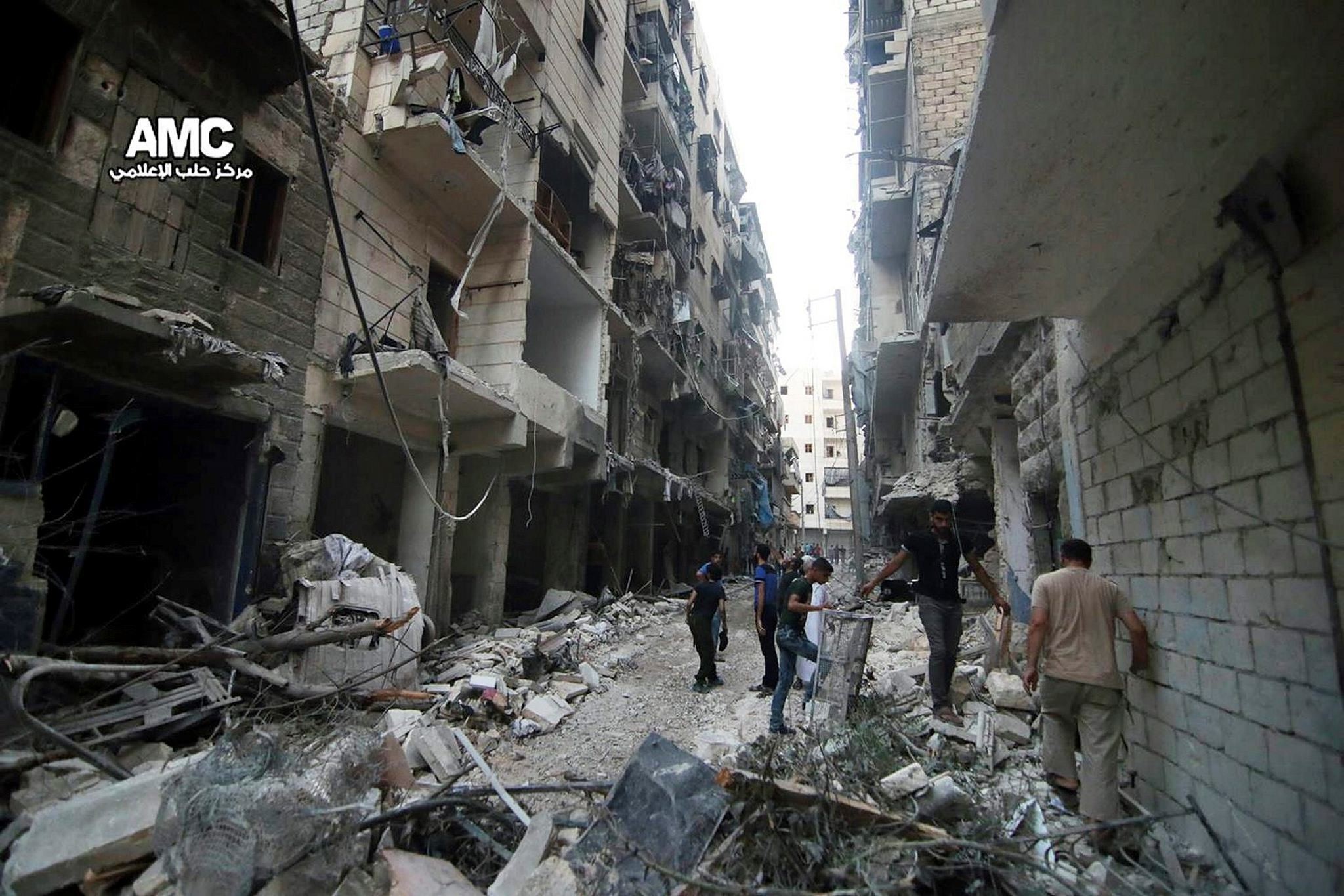 July. 29, 2016 photo, provided by the Syrian anti-government activist group Aleppo Media Center (AMC), shows Syrian citizens inspect damaged buildings after airstrikes hit Aleppo, Syria.