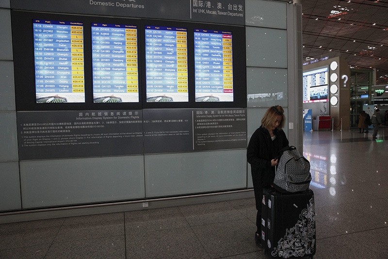 A woman attends to her luggage as flight details are posted on an electronic screen at the Beijing Capital International Airport in Beijing, China, Nov. 21, 2016. (EPA Photo)