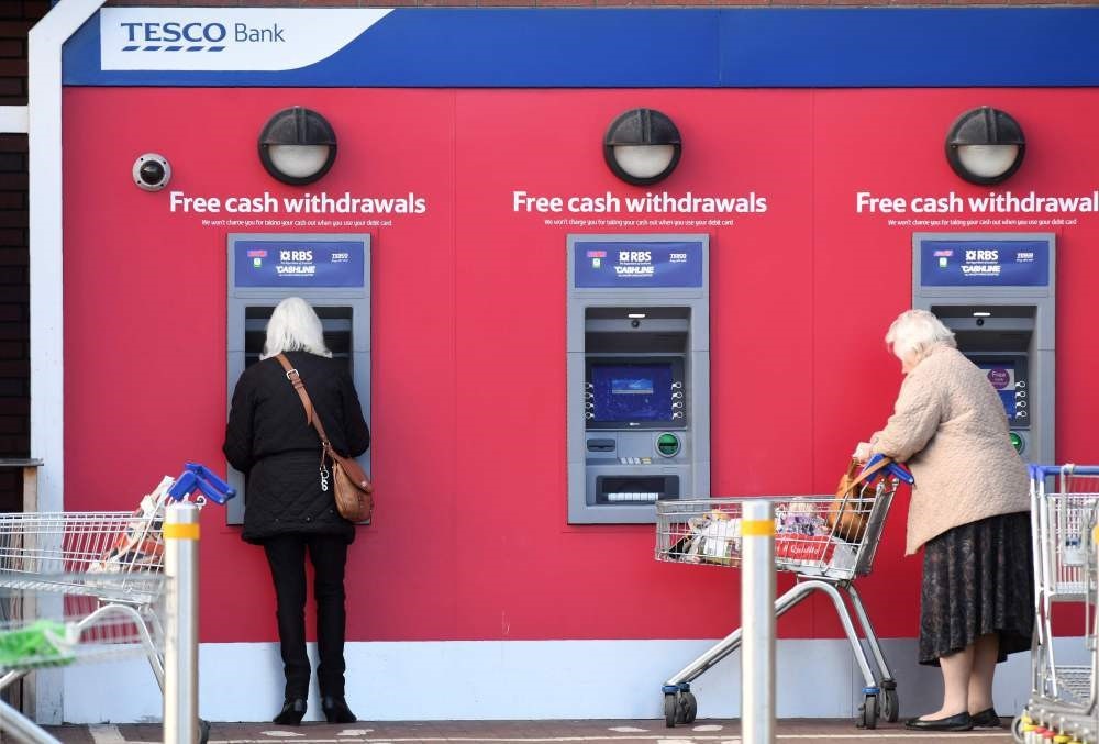 Customers use RBS branded automated teller machines (ATMs) at a Tesco Bank cash point, in Liverpool.