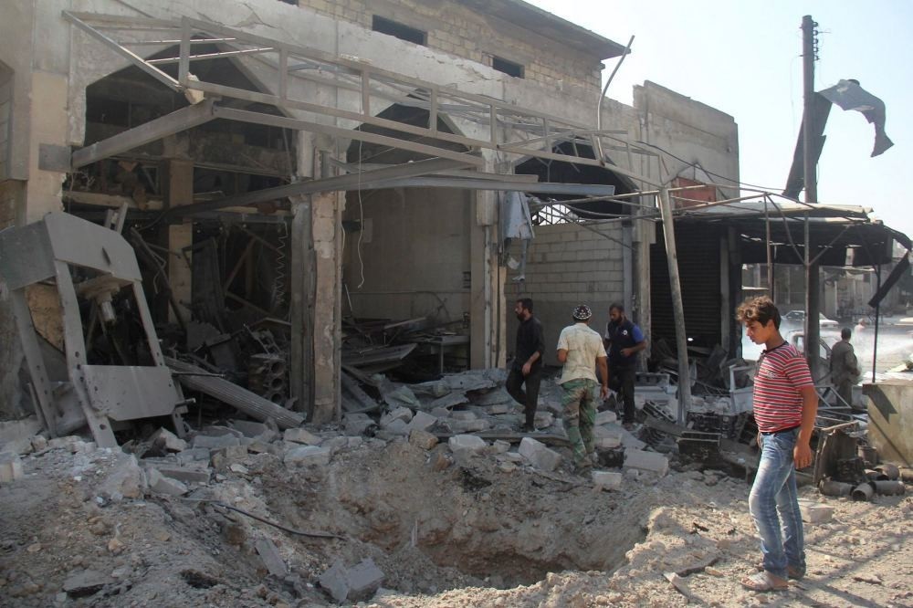 People inspect a damaged building in Idlib after warplanes pounded the city yesterday.