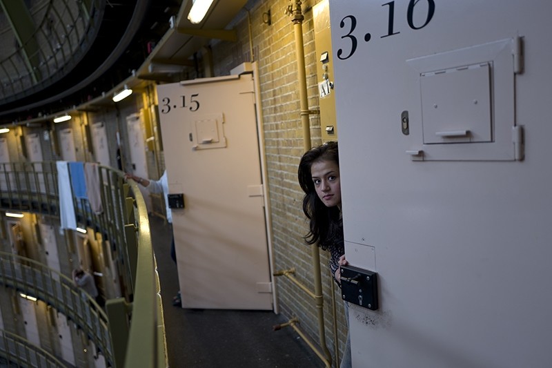 In this Saturday, May 7, 2016 photo, Afghan refugee Shazia Lutfi, 19, peeks through the door of her room at the former prison of De Koepel in Haarlem, Netherlands. (AP Photo)