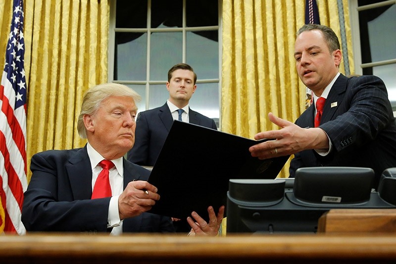 U.S. President Donald Trump hands Chief of Staff Reince Priebus (R) an executive order that directs agencies to ease the burden of Obamacare, after signing it in the Oval Office in Washington, U.S. on Jan. 20, 2017. (Reuters Photo)