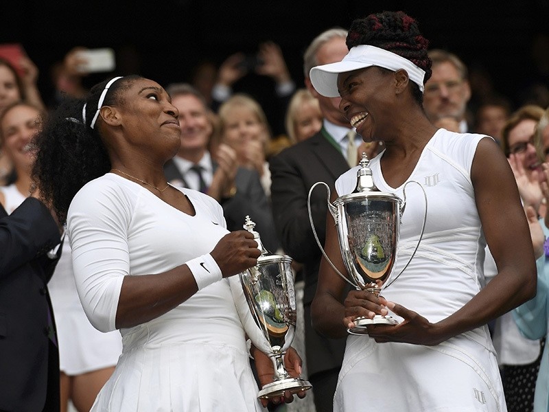 USA's Serena Williams and Venus Williams celebrate winning their womens doubles final against Hungary's Timea Babos and Kazakhstan's Yaroslava Shvedova with the trophies (Reuters Photo)