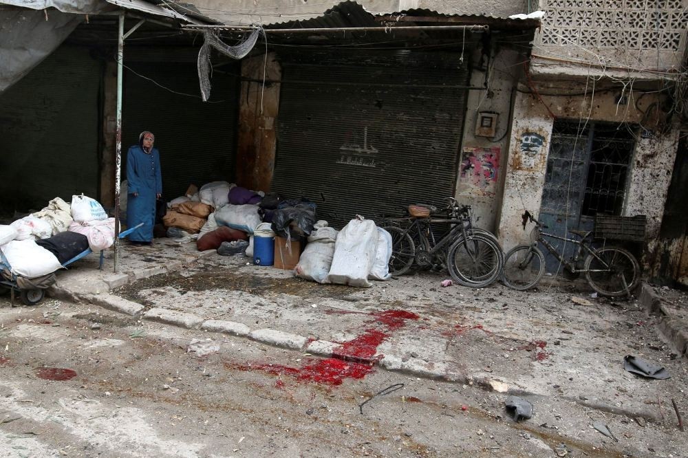 A woman stands near the blood-stained ground after strikes on opposition-held besieged al-Zebdieh district, in Aleppo, Syria, Dec. 5.