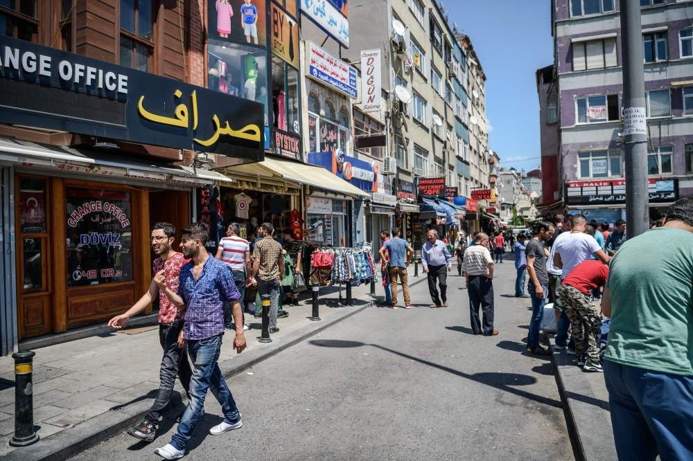 Syrian and Turkish people walk in a street next to shops with Arabic letters in Fatih in Istanbul. (AFP Photo)