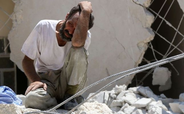  A man looks on as Syrian civil defense workers look for survivors under the rubble of a collapsed building following reported airstrikes on July 17 in the opposition-controlled neighborhood of Karm Homad in the northern city of Aleppo.
