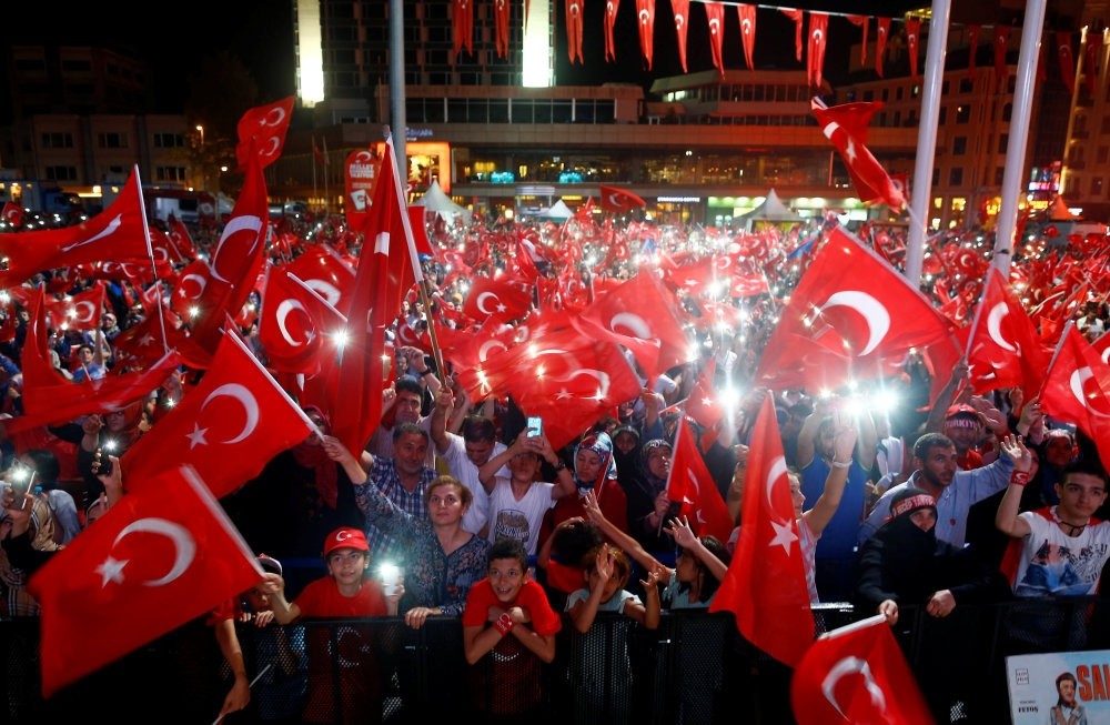 People wave flags as they listen to President Erdou011fan on a giant screen in Istanbul's Taksim Square, Aug. 10.