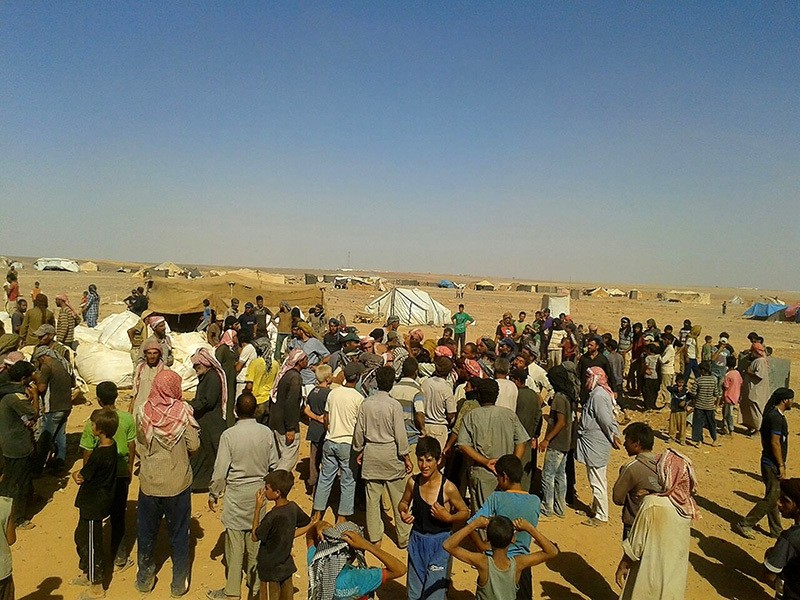 People gather to take basic food stuffs and other aid from community leaders charged with distributing equitably the supplies to the 64,000-person refugee camp called Ruqban on the Jordan-Syria border. (AP Photo)