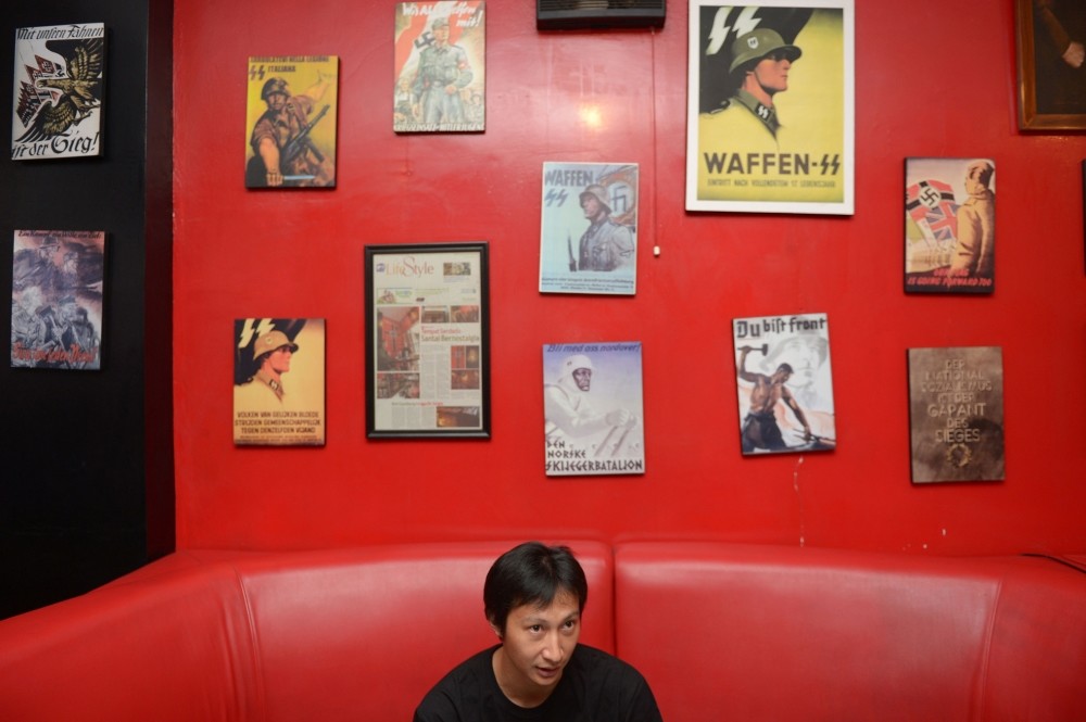 This photo shows owner Henry Mulyana sitting next to images featuring German soldiers during World War II, inside the Soldatenkaffe u201cThe Soldiersu2019 Cafeu201d in Bandung. 