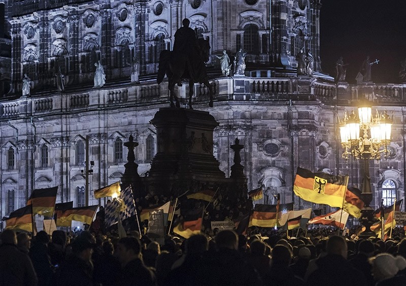 In this file photo dated Dec. 22, 2014, participants of an anti-migrant rally wave German flags. (AP Photo)