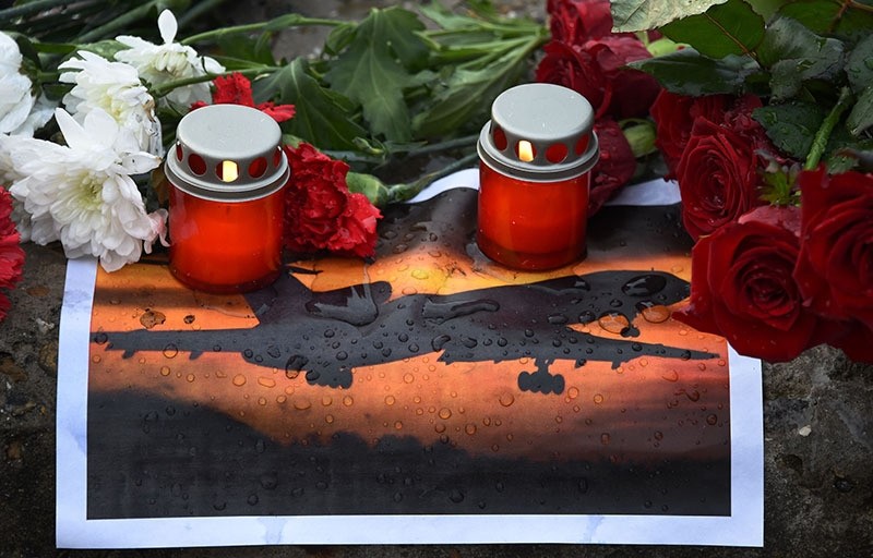 Candles and flowers are laid next to a picture of an airplane at a memorial on a pier outside Sochi, on December 26, 2016, after a military plane carrying 92 people crashed in the Black Sea. (AFP Photo)