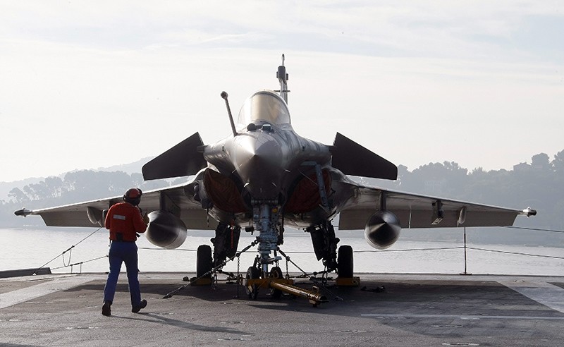 A sailor works at a Rafale jetfighter on the deck of France's nuclear-powered aircraft carrier Charles de Gaulle, at its home port of Toulon, southern France (AP Photo)