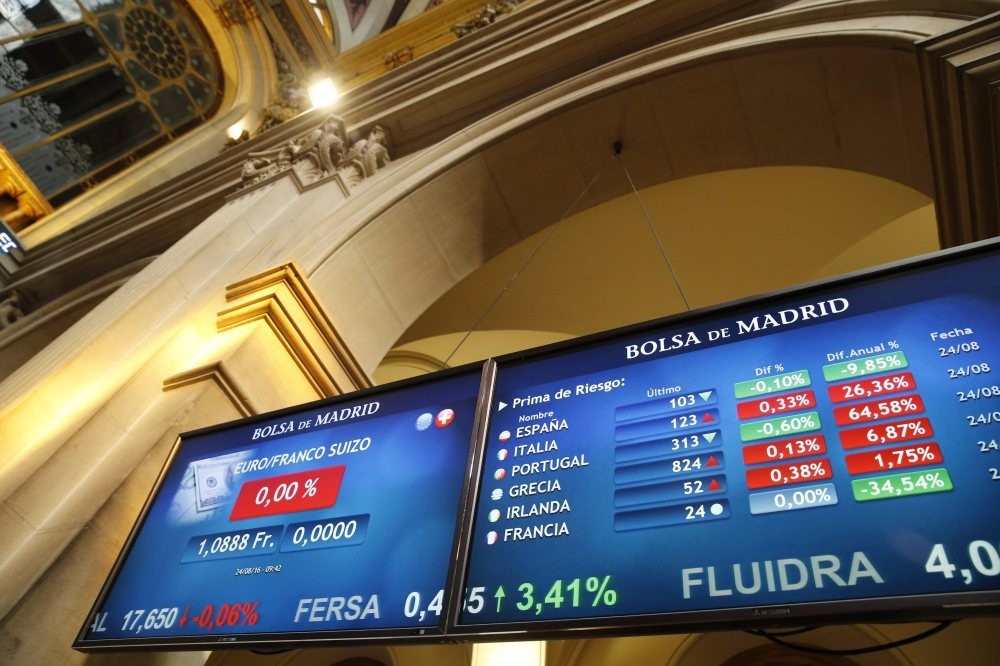 Screens displaying the price of the euro against the Swiss Franc (L) and another showing several European risk premium figures at Madrid's Stock Exchange in Madrid, Spain, on Aug. 24.