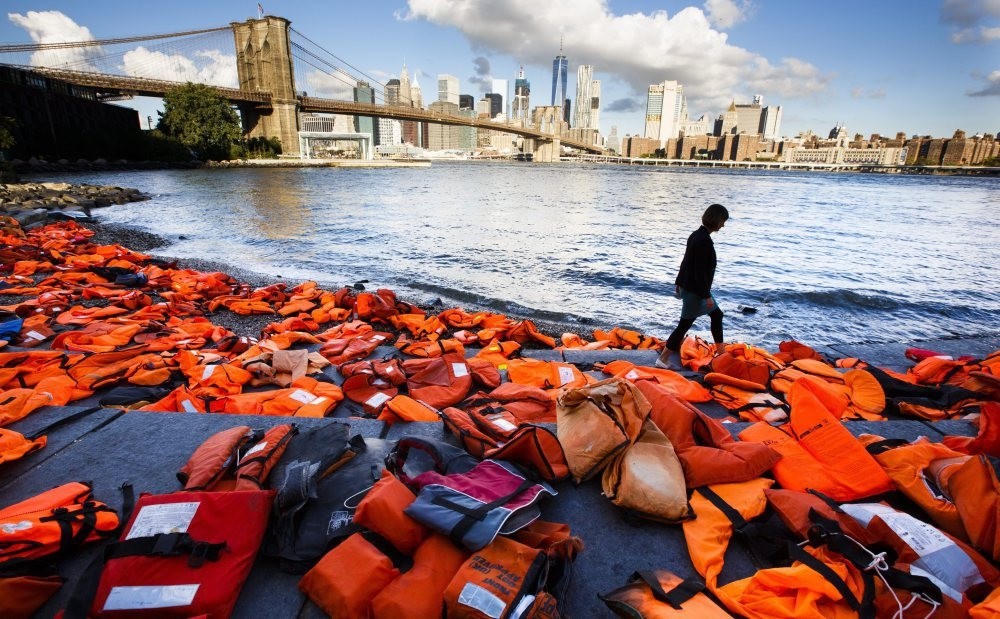 A woman walking past hundreds of refugee life jackets collected from the beaches of Chios, Greece to call attention to the refugee crisis in Brooklyn, New York ahead of the U.N. summit in the city, Sept. 16, 2016.