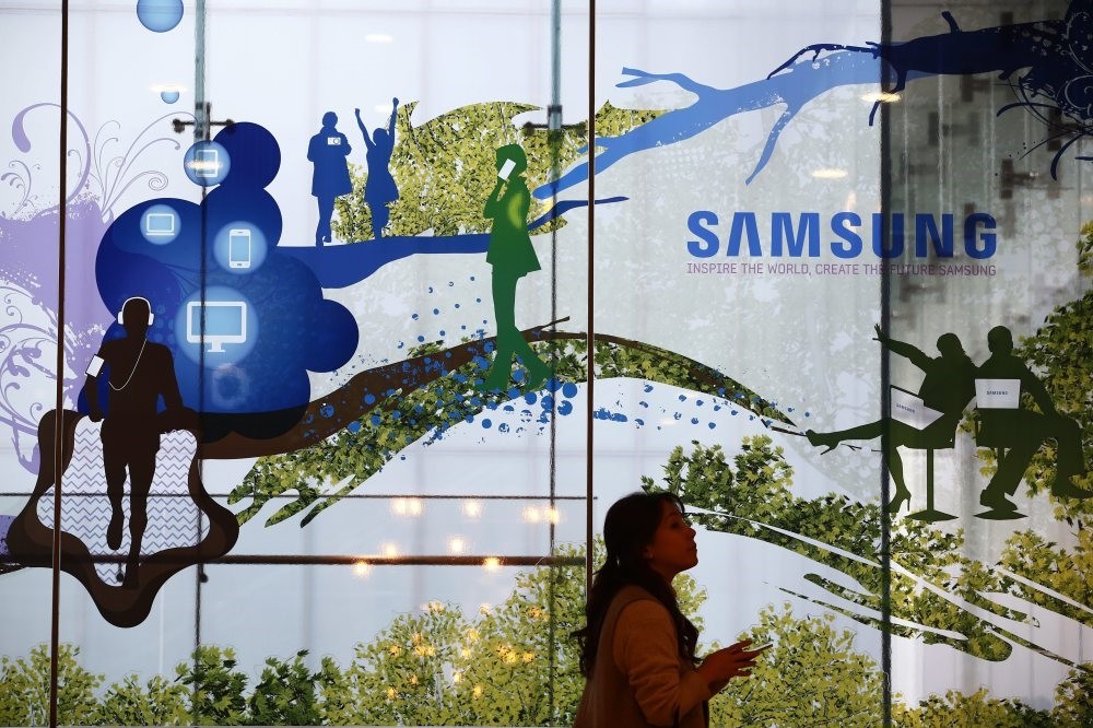 A South Korean woman stands next to an advertisement of Samsung at the Samsung Electronicsheadquarters in Seoul. (EPA Photo)