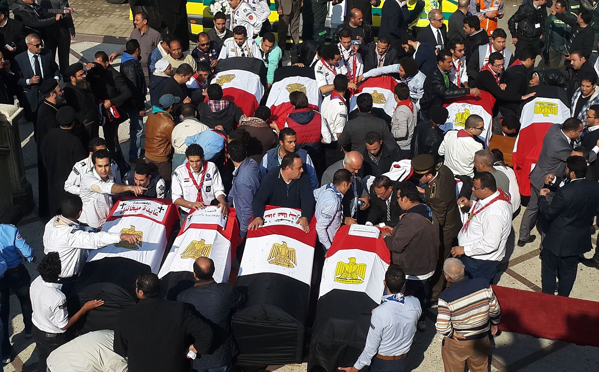 Egyptian mourners and officials stand next to the coffins of the victims of a bomb explosion that targeted a Coptic Orthodox Church in Cairo. (AFP Photo)