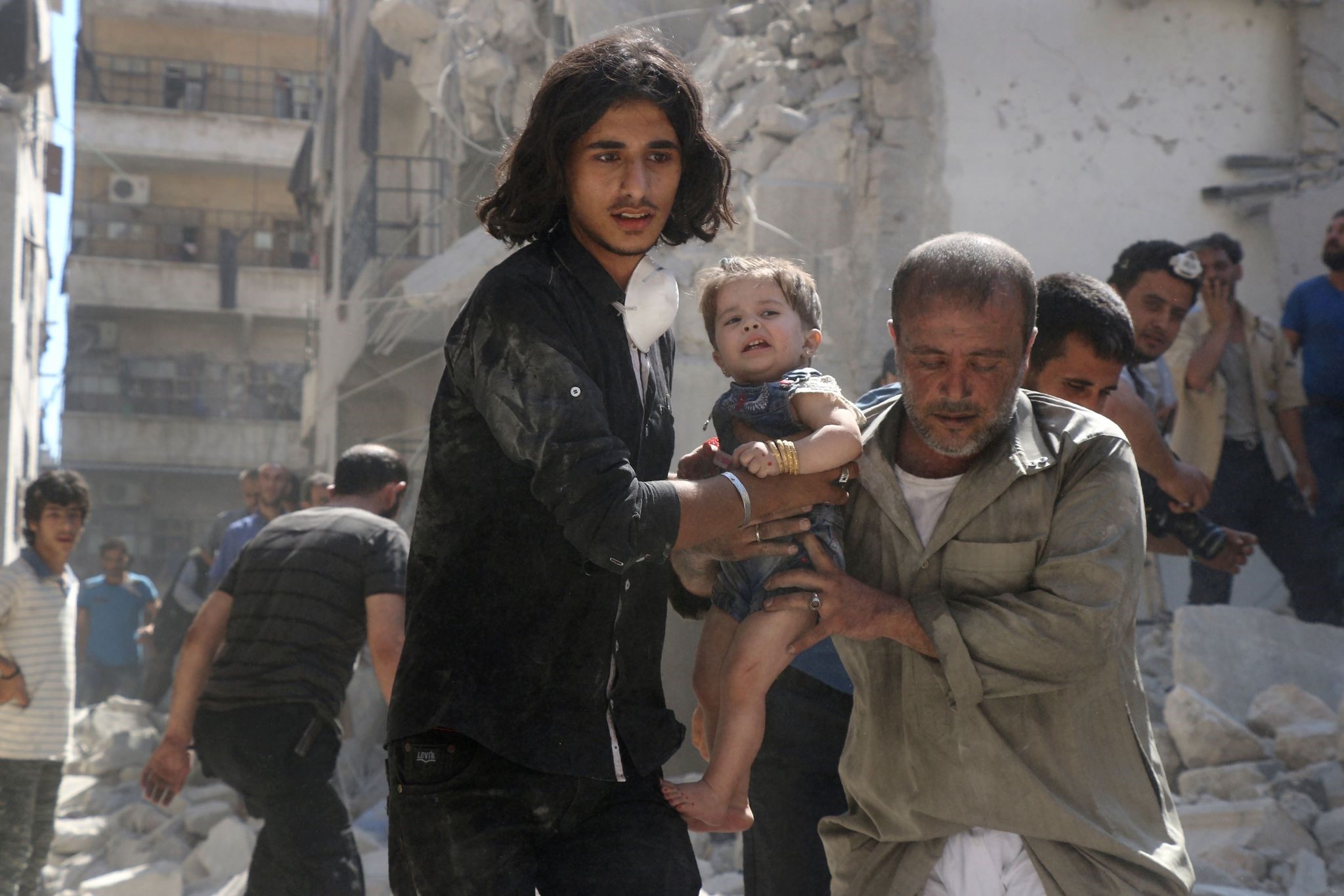 A Syrian civil defence member and a volunteer carry a little girl rescued from under the rubble of destroyed buildings in Aleppo, on September 10, 2016. (AFP Photo)