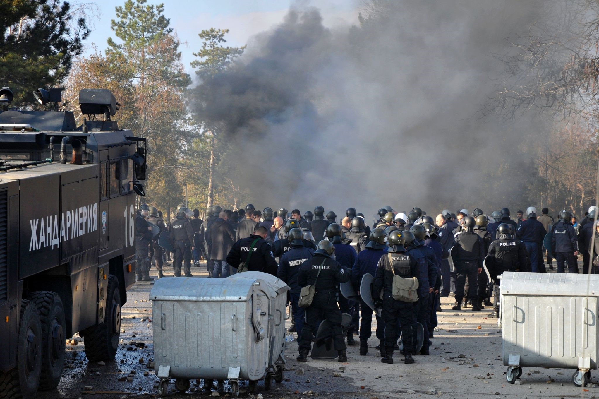 Bulgarian riot police stand near garbarge bins during clashes in the migrants reception centre in the town of Harmanlu0131 on November 24, 2016. (AFP Photo)