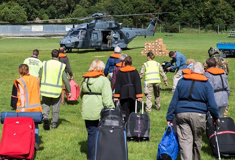 People walking to a helicopeter with their suitcases as hundreds are evacuated from Kaikoura, New Zealand. (AFP Photo) 
