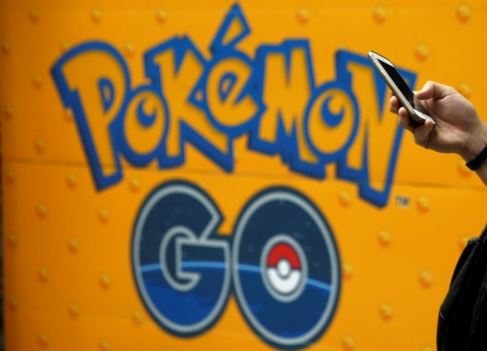 A man uses a mobile phone in front of an advertisement board bearing the image of Pokemon Go at an electronic shop in Tokyo, Japan, July 27, 2016. (REUTERS Photo)