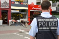 A police officer stands in front of a fastfood restaurant in Reutlingen, southwestern Germany, on July 24, 2016 where a Syrian asylum-seeker killed a woman and injured two people with a machete. (AFP Photo)