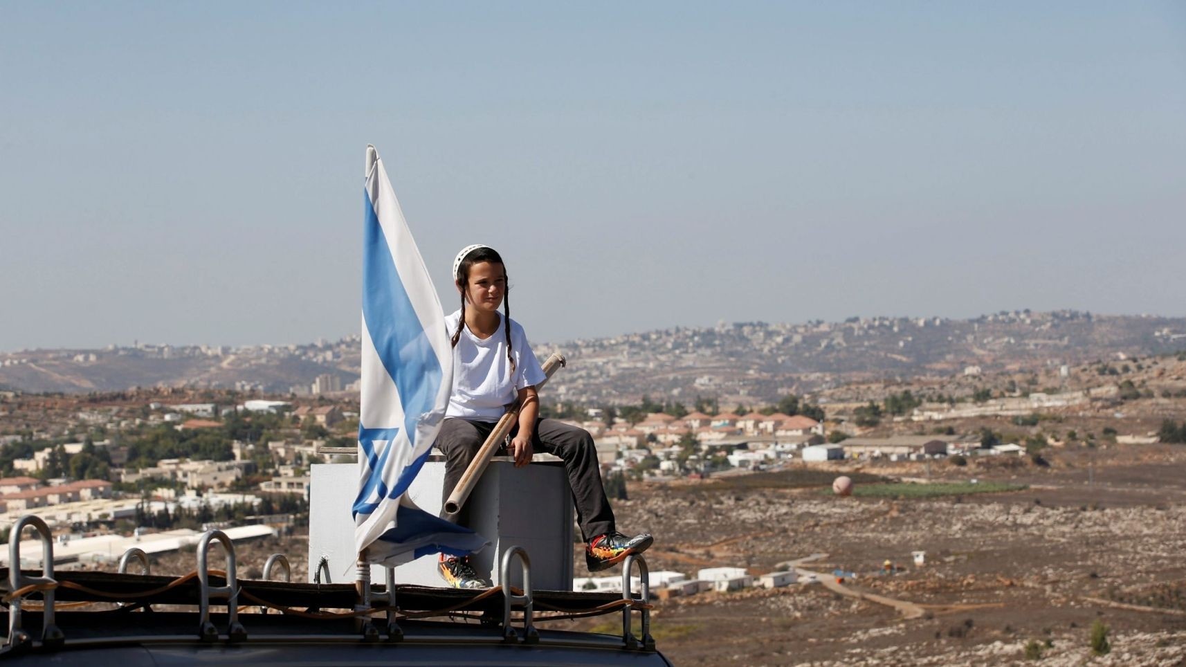 A boy sits on the roof of a vehicle at the entrance to the settler outpost of Amona in the West Bank (Reuters Photo)