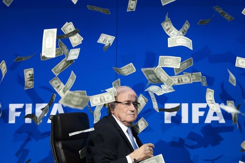 A prankster showers Sepp Blatter with fake dollars at FIFA headquarters in July 2015 (AFP Photo)