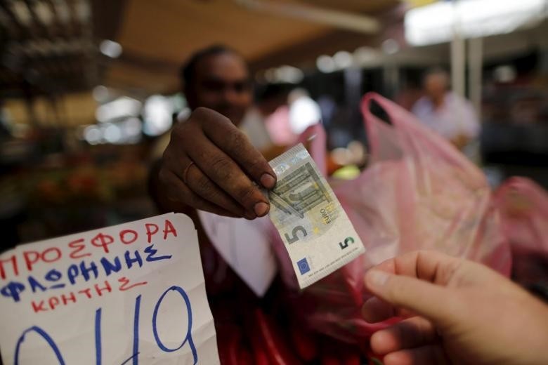 A vendor gives a five Euro bank note back to a customer at the central market in Athens, Greece.