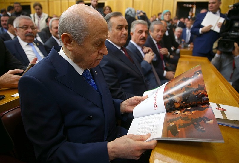 MHP Chair Devlet Bahu00e7eli looks at a magazine in which July 15 coup attempt photos are compiled by Photo Correspondents Association of Turkey before his speech in MHP group meeting. (AA Photo)