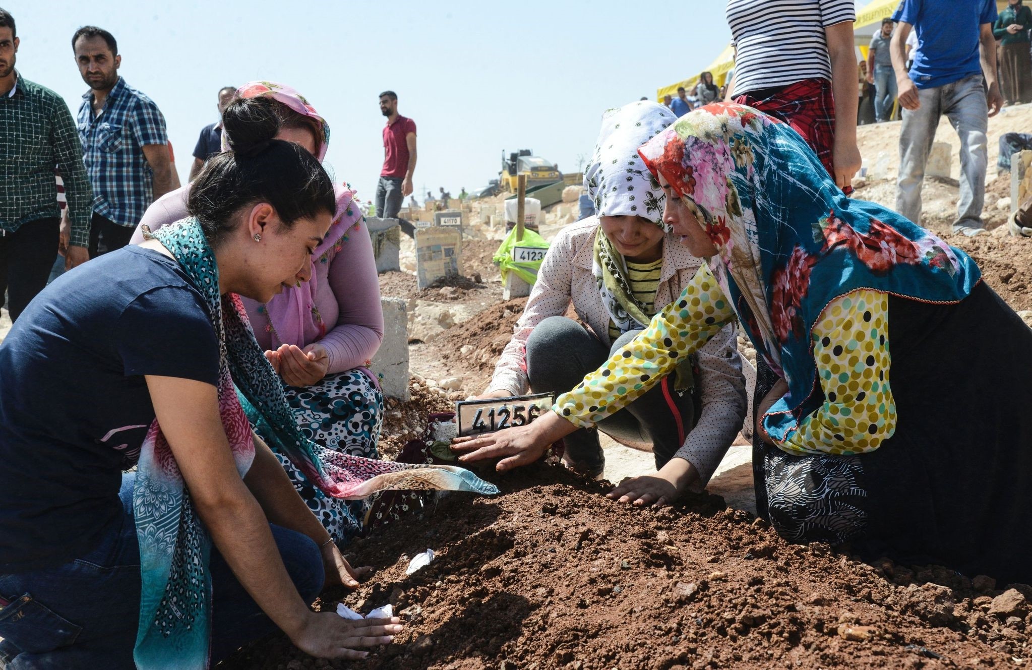 Women gesture as they kneel by a grave at a cemetery during the funeral for the victims of last night's attack on a wedding party that left 50 dead in Gaziantep in southeastern Turke on August 21, 2016. (AFP Photo)