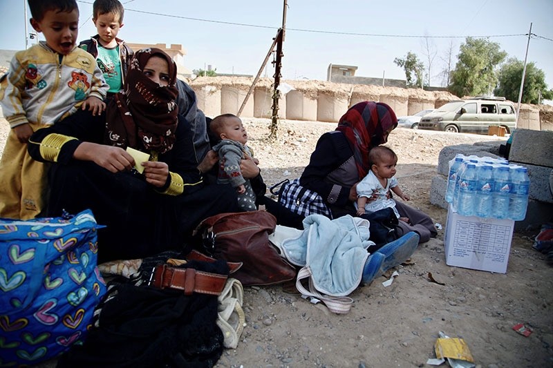 A handout picture release by Save The Children shows displaced Iraqi women, who fled the Islamic State (IS) group held Hawijah area, sitting with their children before being screened at the Dibis checkpoint (AFP Photo)