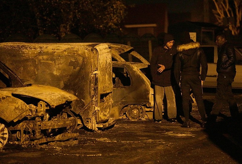 People stand near burnt cars on the street after protesters clashed with police in Beaumont-sur-Oise, north of Paris early on Nov. 24, 2016. (AFP Photo)