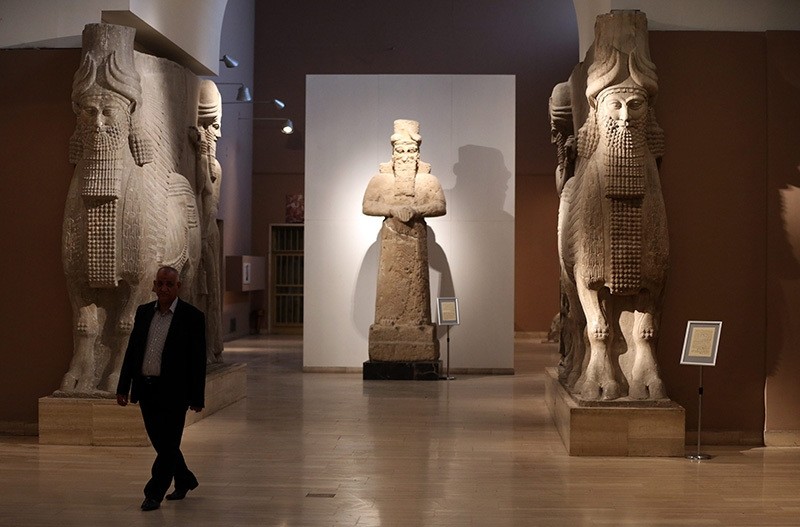 A man at Iraq's National Museum in Baghdad walks past two ancient Assyrian human-headed winged bull statues, March 1, 2015. (AP Photo)