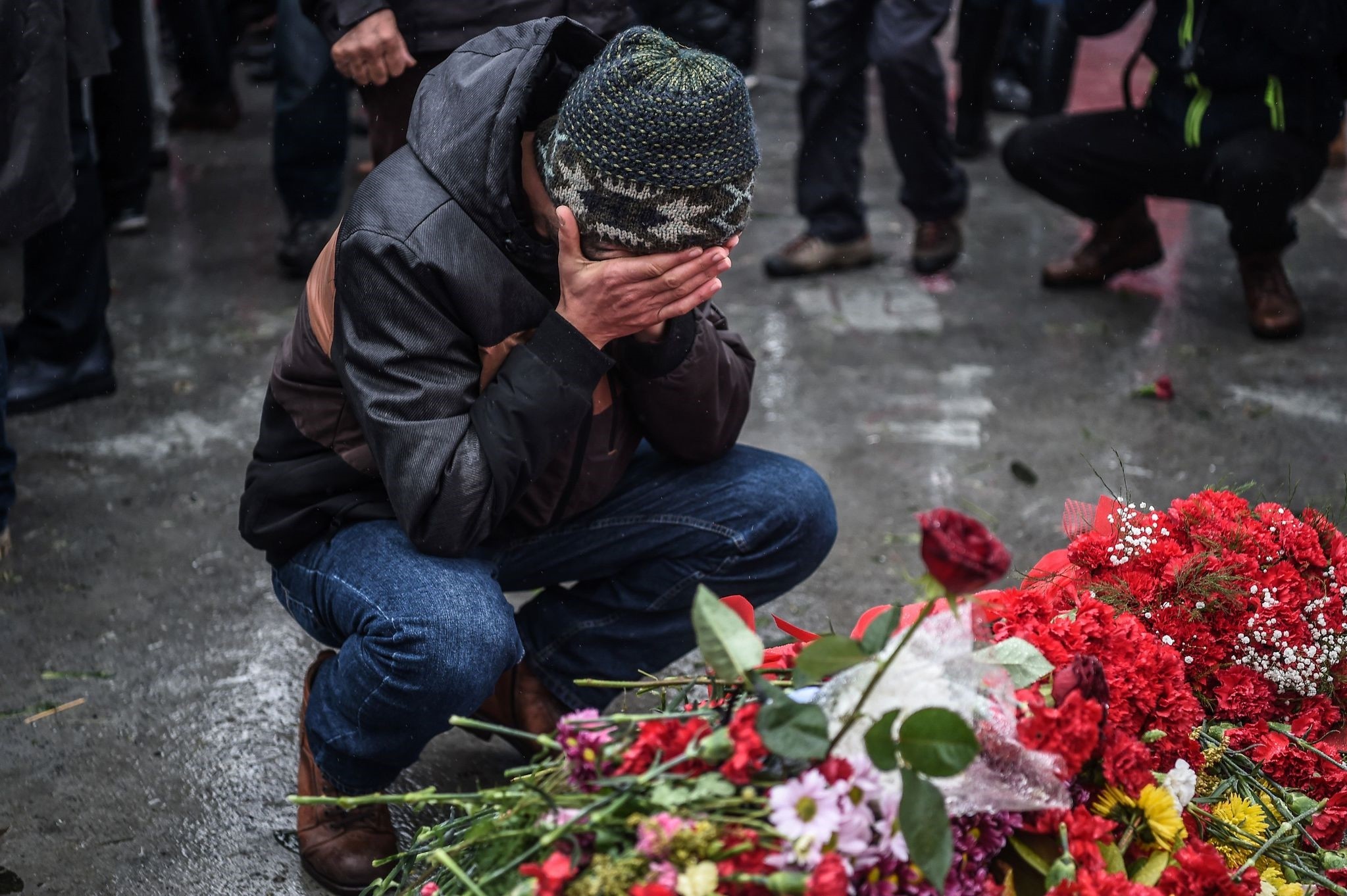 A grieving man reacts before the flowers laid for victims at the site of blasts.