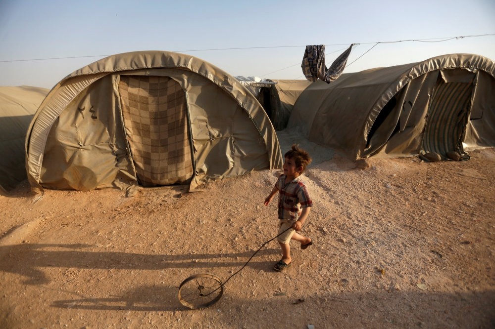 An internally displaced Syrian boy playing with a wheel in Jrzinaz camp, in the southern part of Idlib, Syria, June 21, 2016.