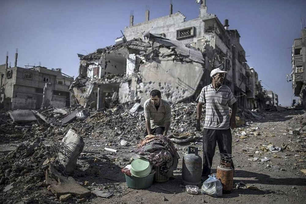 Palestinian men gather things they found in the rubble of destroyed buildings in the Shejaiya residential district of Gaza City.
