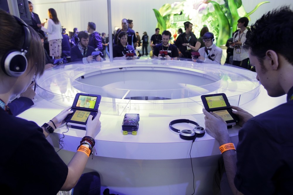 Attendees play video games on the Nintendo 3DS at the Nintendo Wii U software showcase during the E3 game show in Los Angeles.