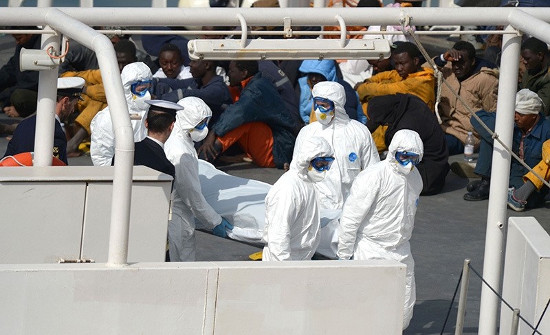 This file photo taken on April 20, 2015 shows rescued migrants watching as the body of a person who died after a fishing boat carrying migrants capsized off the Libyan coast (AFP Photo)