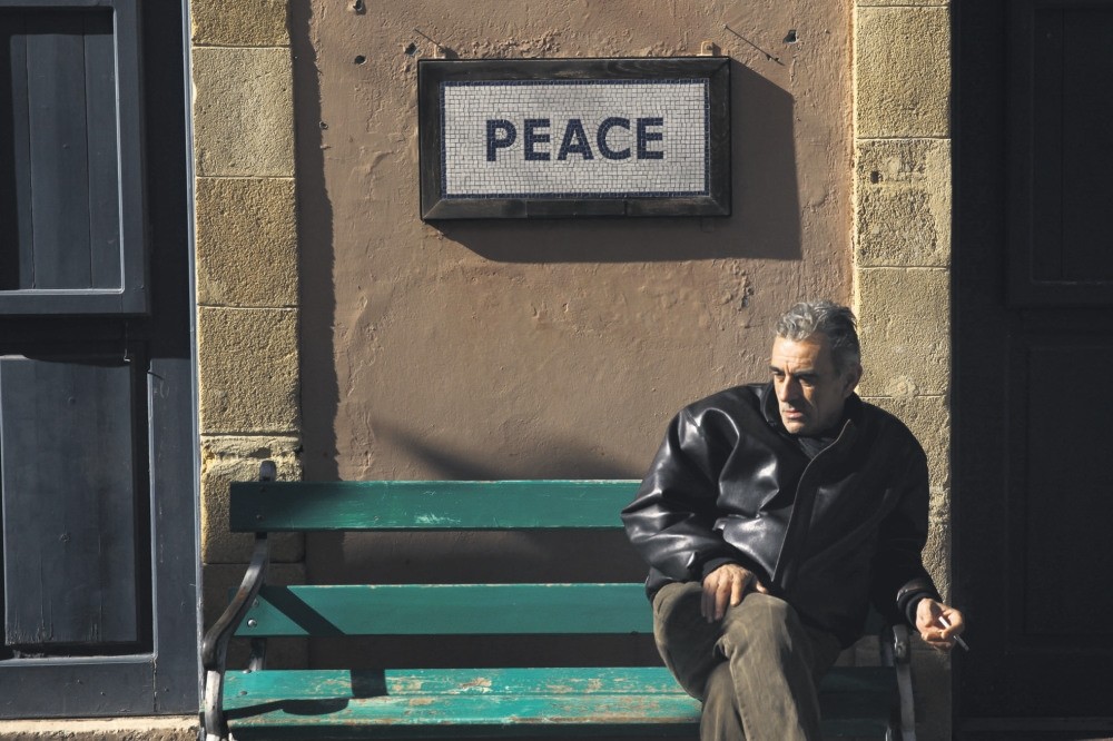 A man sits on a bench under a peace sign near the UN-controlled buffer zone in Nicosia, Cyprus January 9, 2017. (Reuters Photo)